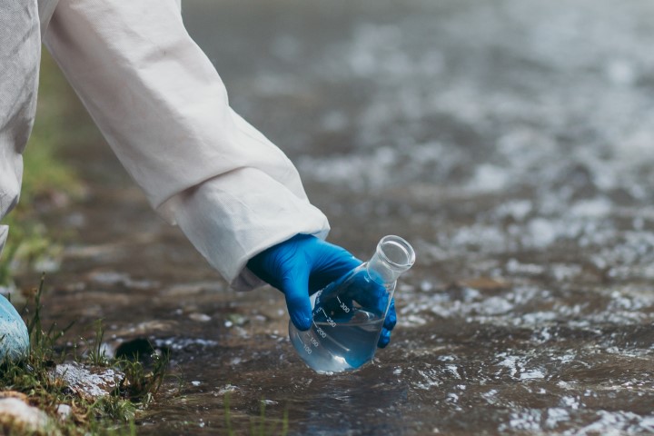 photo of person scooping up river water for analysis