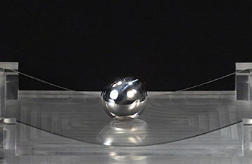 When a steel ball is dropped on a sheet of Dinorex to test its strength, the ball bounces off and the glass does not break.